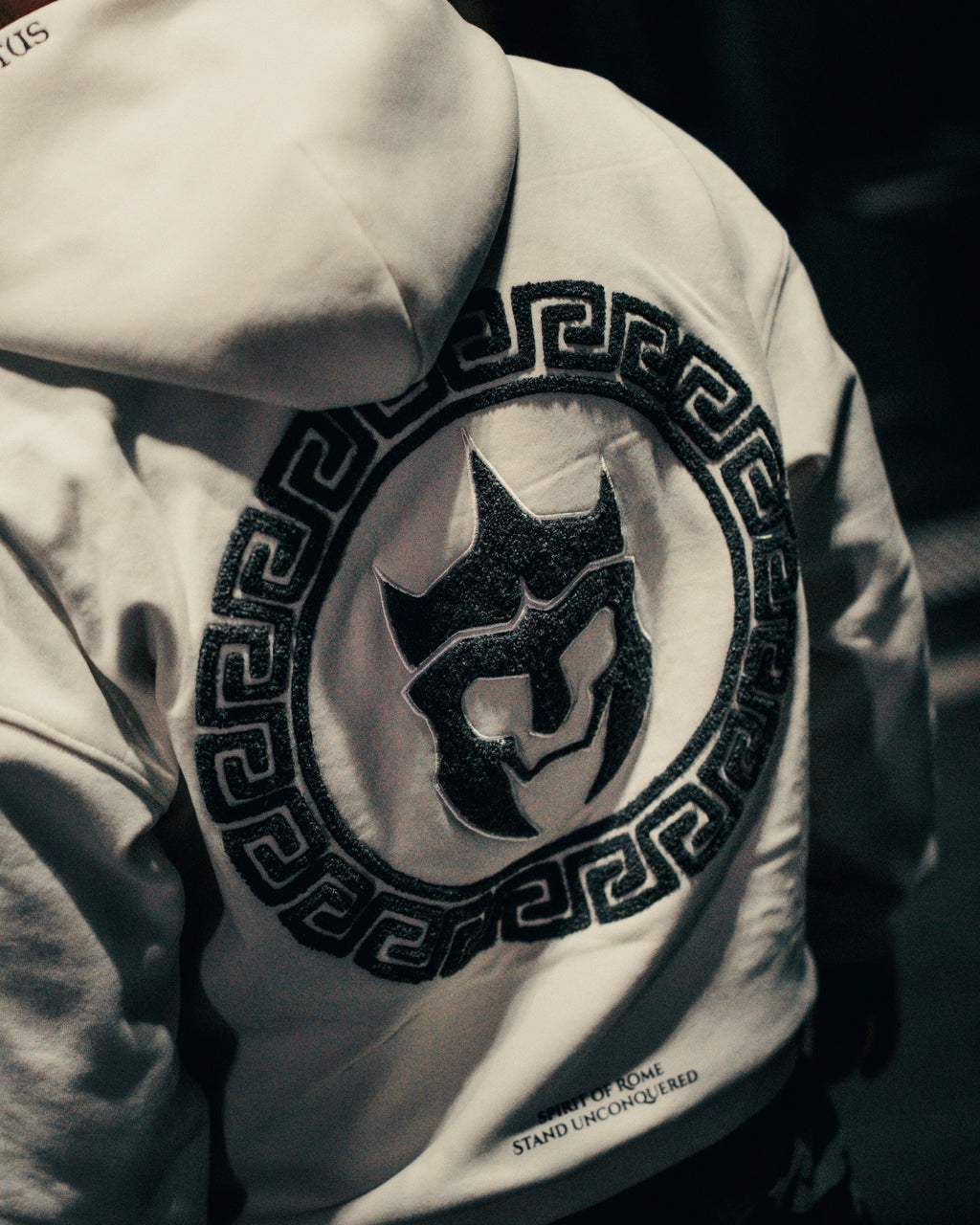 Close-up of an off-white hoodie with a black logo on a dark background