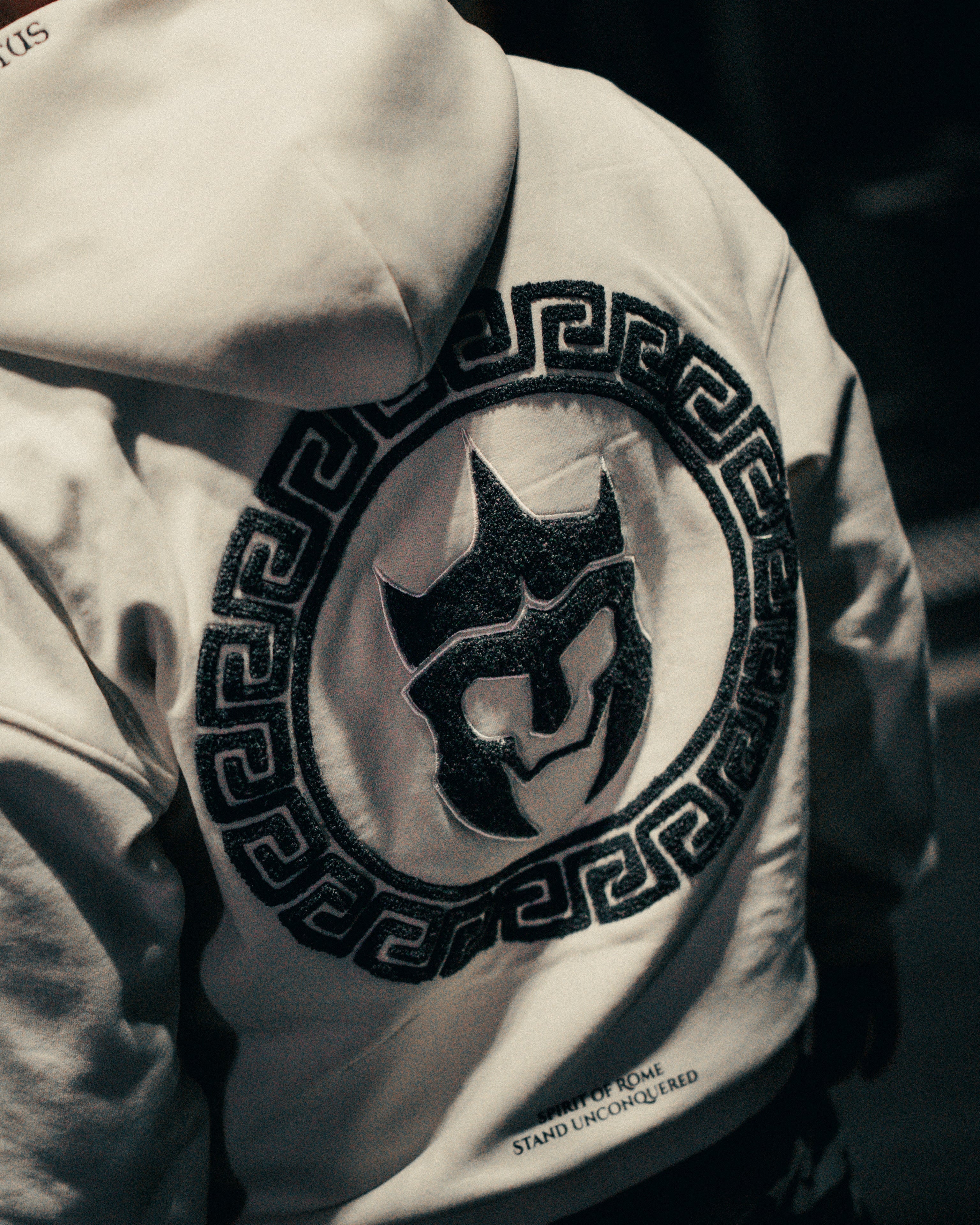Close-up of an off-white hoodie with a black logo on a dark background